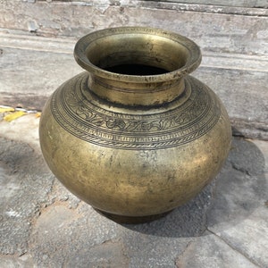 May include: A large, round, brass vase with intricate etched designs. The vase has a wide mouth and a narrow base. It is a traditional Indian design.