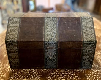 May include: A vintage wooden chest with a hinged lid and a metal latch. The chest is decorated with silver-colored metal strips and has a distressed look.