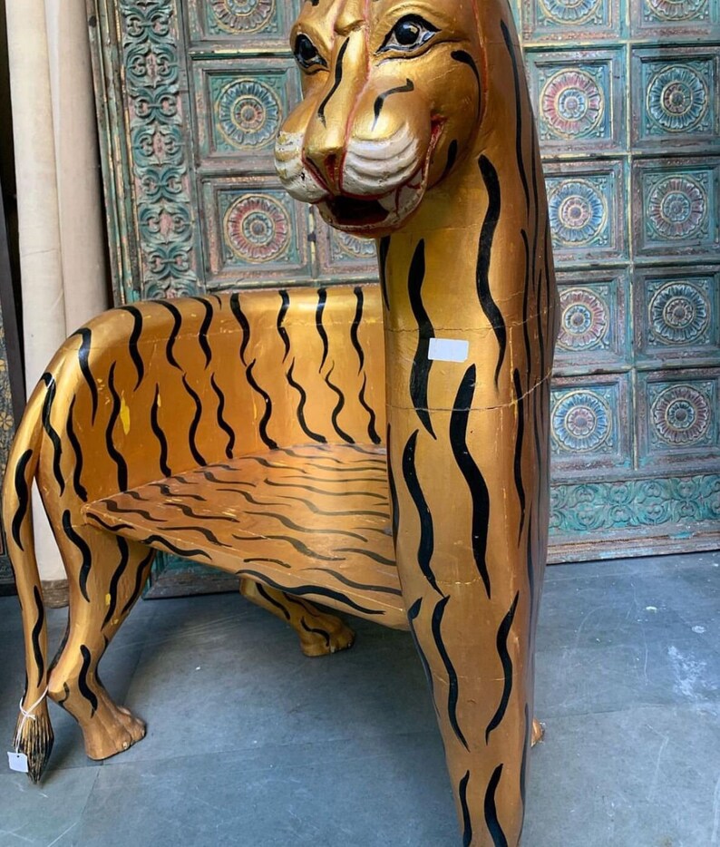May include: A wooden chair shaped like a tiger with gold and black stripes. The chair has a seat and a back.