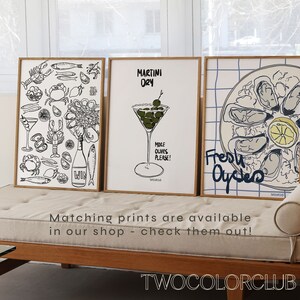 以下が含まれることがあります： 食べ物と飲み物のイラストが描かれた、額入りのアートプリント3枚。1つはシーフード、もう1つはオリーブ入りのマティーニ、3つ目はカキです。プリントは黒、白、青で、「MARTINI DRY」と「Fresh Oysters」の文字が入っています。