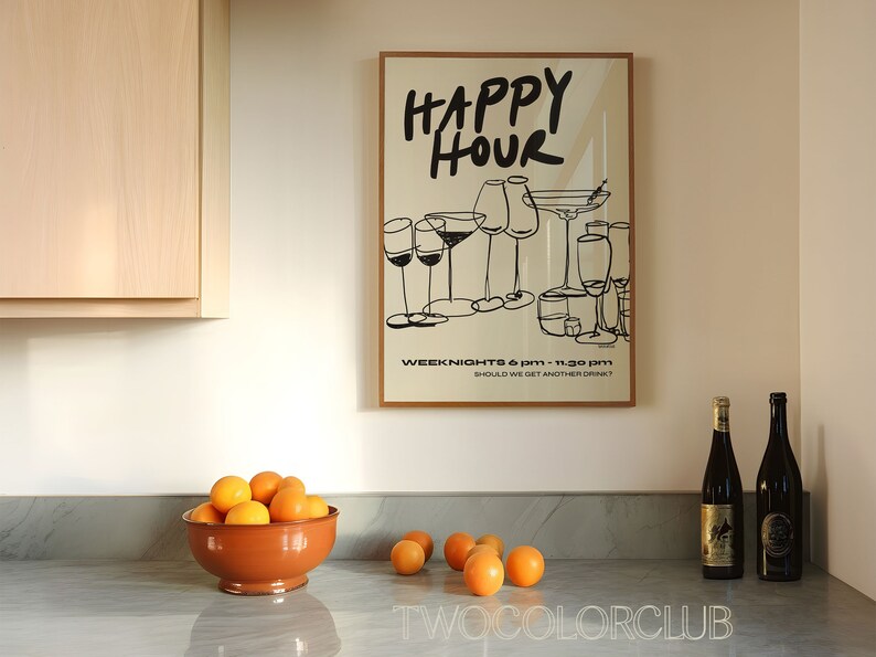 May include: A framed poster with the text "HAPPY HOUR" in black script. The poster features a black and white illustration of various glasses of wine and cocktails. The text "WEEK NIGHTS 6 PM - 11:30 PM" and "SHOULD WE GET ANOTHER DRINK?" is printed below the illustration. Two bottles of wine are on a gray countertop with a bowl of oranges.