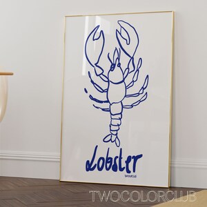 K&ouml;nnte beinhalten: Ein wei&szlig;er gerahmter Poster mit einer blauen Linienzeichnung eines Hummers. Der Poster hat das Wort "Lobster" in blau unter der Zeichnung und den Text "TWOCOLORCLUB" in kleineren blauen Buchstaben unter dem Wort "Lobster" geschrieben.