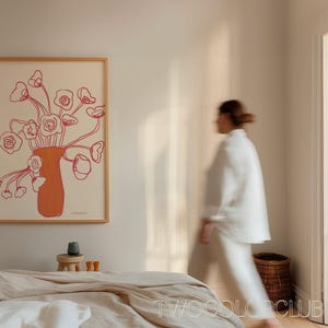Może przedstawiać: Minimalistyczny druk liniowy wazonu z r&oacute;żowymi kwiatami. Druk jest oprawiony w jasną drewnianą ramę i wisi na białej ścianie.