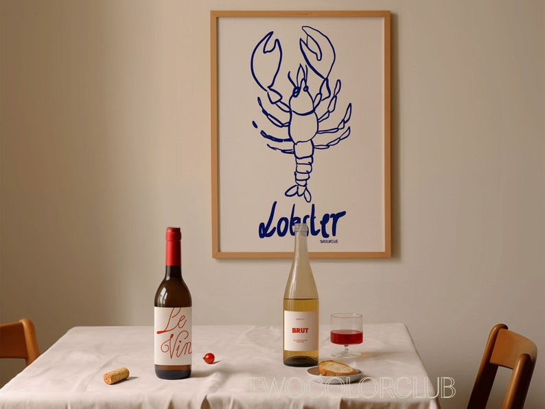 K&ouml;nnte beinhalten: Ein wei&szlig;er Tisch mit einer wei&szlig;en Tischdecke, ein Korken, eine Rotweinflasche mit einem wei&szlig;en Etikett, auf dem "Le Vin" steht, eine rote Kirsche, ein klares Glas Rotwein, eine klare Flasche Wei&szlig;wein mit einem wei&szlig;en Etikett, auf dem "BRUT" steht, ein St&uuml;ck Brot auf einem kleinen wei&szlig;en Teller und ein gerahmter Druck eines blauen Hummers mit dem Wort "Lobster" darunter.