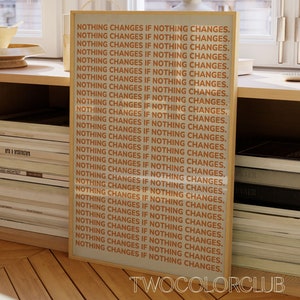 Puede incluir: Una impresión enmarcada con el texto "NOTHING CHANGES IF NOTHING CHANGES." repetido 28 veces. El texto es de color naranja sobre un fondo blanco. El marco es de madera marrón claro. La impresión está en un estante con libros.