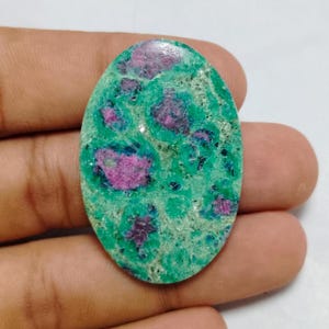 May include: Oval-shaped green and pink gemstone cabochon with a mottled pattern.