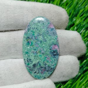 Puede incluir: Cabujón ovalado de piedra preciosa verde, azul y rosa con un patrón moteado.