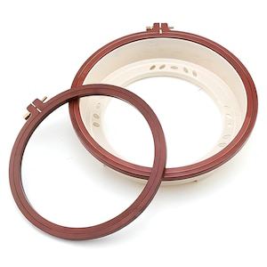 May include: Two embroidery hoops, one larger than the other, both with a brown wooden frame and a white plastic inner ring. The larger hoop has a screw-on mechanism.