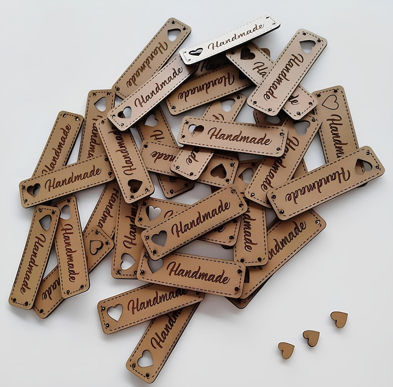May include: A pile of brown wooden tags with the word "Handmade" engraved on them. Each tag has a heart-shaped cutout.