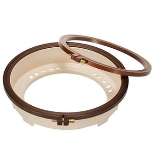 May include: A brown embroidery hoop with a white inner ring. The hoop is made of two separate rings that can be adjusted to fit different sizes of fabric.