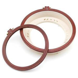 May include: Two embroidery hoops, one inside the other. The larger hoop is made of brown wood with a white plastic insert. The smaller hoop is made of brown wood.