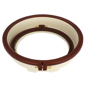 May include: A white and brown embroidery hoop with two adjustable clamps. The hoop is made of plastic and has a smooth, rounded edge.