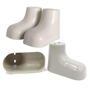 Op de afbeelding: Een set van vier off-white keramische zout- en peperstrooiers in de vorm van schoenen, samen met een bijpassende rechthoekige container. De strooiers hebben een glanzende afwerking en een minimalistisch ontwerp.
