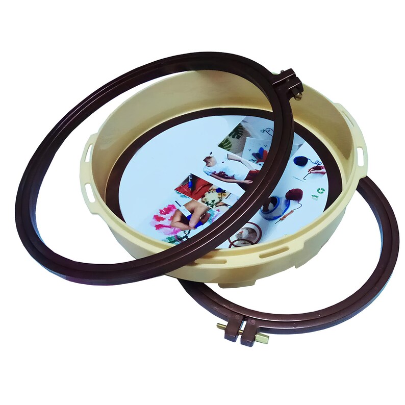 May include: A set of two brown embroidery hoops with a cream-colored plastic base. The base has a printed image of people using the hoops.