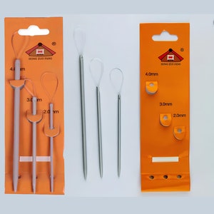 Op de afbeelding: Drie sets breinaalden verpakt op oranje kaarten. De naalden zijn in verschillende maten: 2,0 mm, 3,0 mm en 4,0 mm. De naalden zijn gemaakt van metaal en hout.