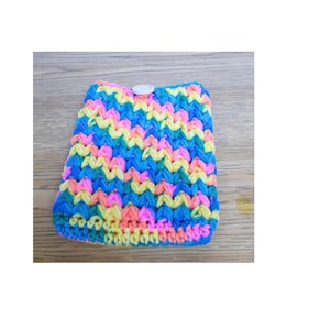 Peut inclure: Une pochette crochetée à la main aux couleurs vives : bleu, jaune, rose et orange. Le motif de point texturé crée un design unique. Un bouton blanc ferme le rabat supérieur. La pochette est probablement utilisée pour de petits objets.