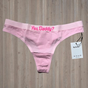 Può includere: Slip rosa con la scritta "Yes, Daddy?" in lettere rosa. Lo slip ha un'etichetta bianca con la scritta "BySofia" in lettere nere.