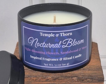 May include: A black metal candle tin with a white wax fill and a single wick. The label is purple with white text reading Temple & Thorn Nocturnal Bloom, Night-Blooming Flowers, Sandalwood & Moss, Inspired Fragrance & Ritual Candle, Net Wt. 3.1 oz.