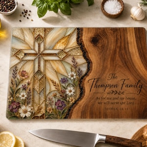 May include: A rectangular glass cutting board featuring a stained-glass style cross design with floral accents on the left and a natural wood grain pattern on the right. The text reads: The Thompson Family, As for me and my house, we will serve the Lord, JOSHUA 24:15.