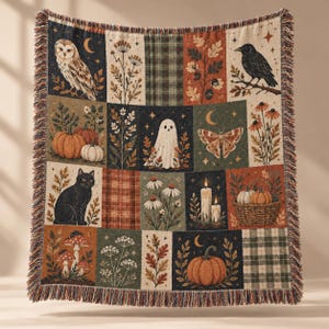 May include: A woven throw blanket featuring a grid of autumnal illustrations including an owl, a black cat, a ghost, a raven, pumpkins, mushrooms, wildflowers, candles, and moths in a palette of orange, green, brown, and cream with fringe.