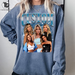 May include: A blue sweatshirt with the word "CUSTOM" printed in a blue and white gradient. The sweatshirt features a collage of five women with different hairstyles and clothing.