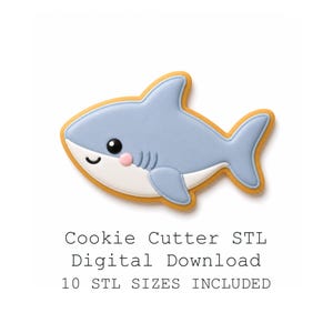 Op de afbeelding: Een lichtblauw en wit haai-vormig koekjesvormontwerp met een gele rand. De haai heeft een lachend gezicht, een zwart oog en een roze wang. De tekst eronder luidt: Cookie Cutter STL Digital Download, 10 STL SIZES INCLUDED.