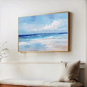 a large painting of a serene ocean scene hanging on a white wall above a wooden bench.