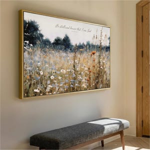 a large painting of a field with flowers hanging on a wall, accompanied by a bench in the foreground.