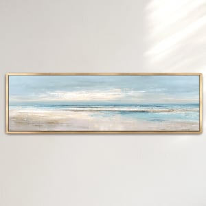 May include: An abstract landscape painting of a beach scene. The artwork features a light blue sky, white clouds, and a sandy beach with blue and white waves. The painting is framed in a gold-colored rectangular frame.