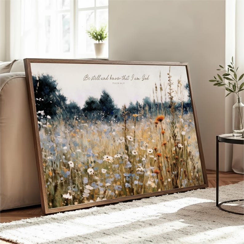 A framed painting depicting a field of flowers is displayed on a wooden floor in a living room.