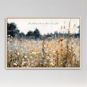 The image is a painting of a field filled with wildflowers, including daisies and other colorful blooms. The painting is framed and hangs on a wall.