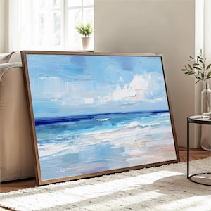 a large painting of a serene ocean landscape, with a blue sky and white clouds, displayed on a wooden frame and placed on a white rug in a living room setting.