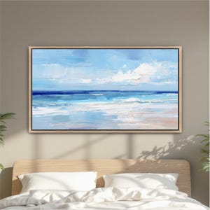 a large, framed painting of a serene ocean landscape hanging on a wall above a bed with white pillows.