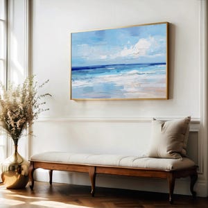 a large painting of a serene beach scene hanging on a white wall, with a wooden bench and a vase of flowers placed in front of it.