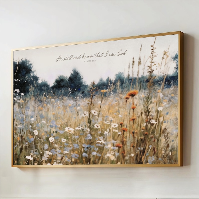 The image is a framed painting depicting a field of wildflowers, with a text overlay that reads "Be still and know that I am God" from Psalm 46:10.