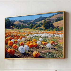 May include: A framed landscape painting depicts a pumpkin patch with orange and white pumpkins. The pumpkins are in a field with green grass and colorful wildflowers. Rolling hills and a blue sky are in the background.