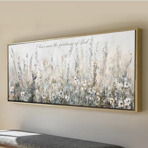 May include: A rectangular wall art piece in a gold frame featuring a painting of wildflowers in shades of white, gray, and beige. The text "I have seen the goodness of God" is written in a cursive script across the upper portion of the canvas.