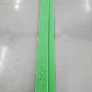 May include: Two bright green, rectangular strips are displayed vertically. The text "1.25cm" is printed on one of the strips. The strips are side by side, and the background is a light gray color.