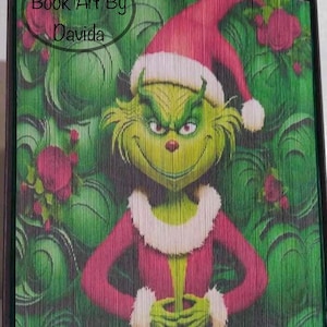 May include: A green Grinch wearing a red Santa hat and a red and white suit, with a green background of swirling leaves and red roses. The text "Book Art By Davida" is in the top left corner.