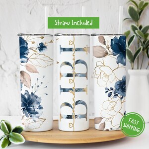 May include: Three stainless steel tumblers with a white background and a blue and gold floral design. The middle tumbler has the name "Pippa" written in gold cursive script.