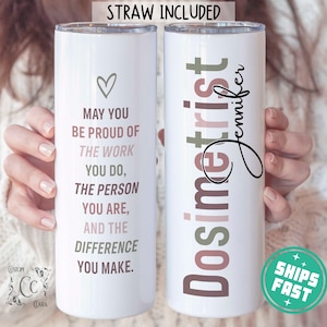 May include: Two white insulated tumblers with text and graphics. One tumbler has a heart graphic and the text "May you be proud of the work you do..." The other says "Dosimetrist Jennifer" with a green and pink color scheme.