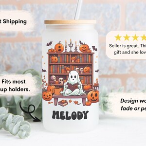 May include: A white reusable tumbler with a ghost reading a book in front of a bookshelf with pumpkins and bats. The tumbler has a bamboo lid and a straw. The text "MELODY" is printed on the front of the tumbler.