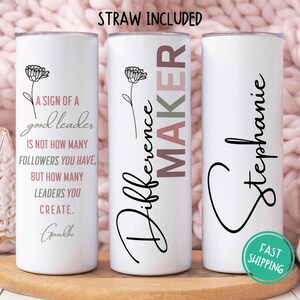 May include: Three white stainless steel tumblers with black text and floral designs. The first tumbler says "A sign of a good leader is not how many followers you have, but how many leaders you create. Gandhi". The second tumbler says "Difference Maker" with a pink and green gradient. The third tumbler says "Stephanie".