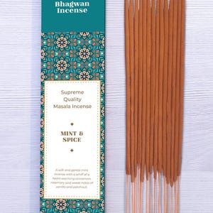 Puede incluir: Un paquete de incienso Bhagwan, sabor Menta y Especias, con un diseño turquesa y estampado. Un paquete de incienso marrón está al lado. El texto en el paquete dice "Supreme Quality Masala Incense".