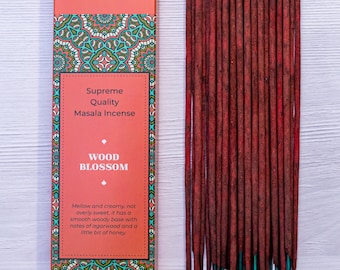 Puede incluir: Una caja de inciensos Wood Blossom con un diseño de mandala rojo y verde. La caja dice "Bhagwan Incense, Supreme Quality Masala Incense, Wood Blossom, Mellow and creamy, not overly sweet, it has a smooth woody base with notes of agarwood and a little bit of honey."