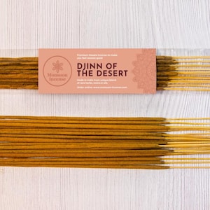 May include: Two packs of incense sticks, labelled "Djinn of the Desert" by Monsoon Incense, are displayed on a light wood-grain surface. The incense sticks are light brown with yellow tips. The packaging is a light peach colour.