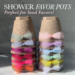 May include: A stack of small brown biodegradable pots with tulle bows in various colors, including pink, purple, blue, green, yellow, and orange. The pots are labeled "Shower Favor Pots" and "Perfect for Seed Favors!"