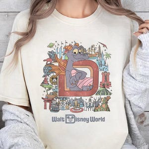 a woman sitting on a bed wearing a t - shirt