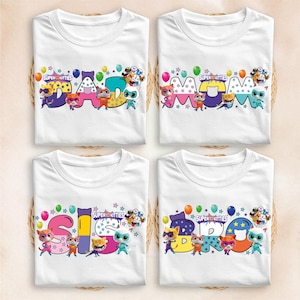 four white t-shirts with colorful text and characters printed on them.