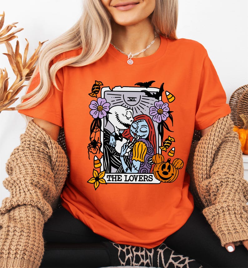 A woman wearing an orange t-shirt with a graphic design featuring characters from the movie "The Jack Skellington".